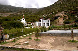The park and performance area in the foreground, with the guest house and stūpa behind it.