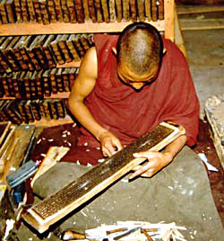 A young monk works with a woodblock from which he will print a text.